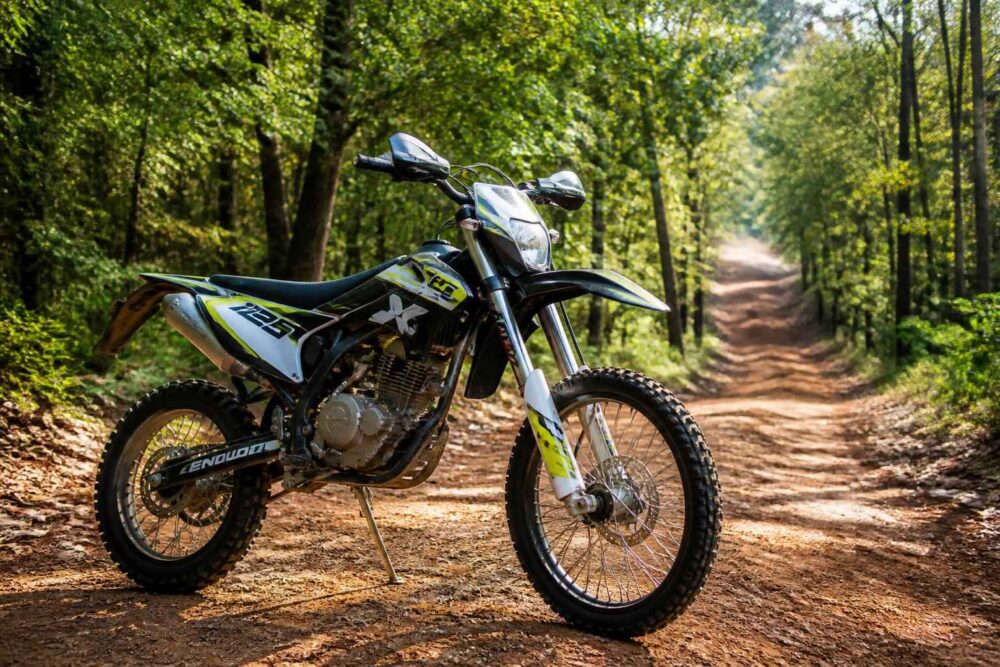 Motocykl crossowy stojący na leśnej drodze wśród drzew