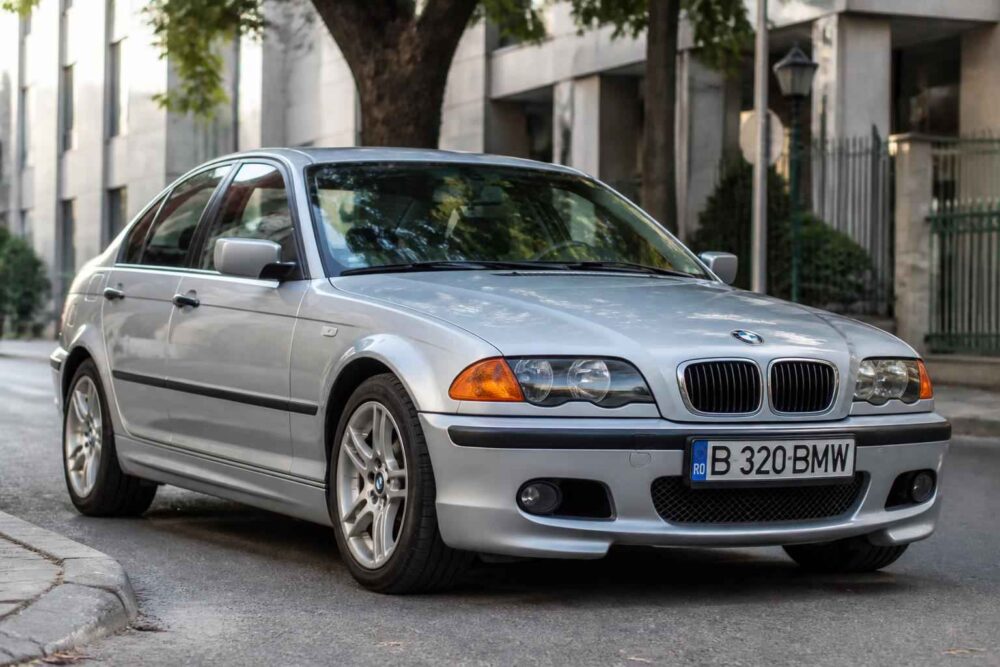 Srebrne BMW E46 zaparkowane przy ulicy Srebrne BMW E46 z polską tablicą rejestracyjną stojące przy miejskiej kamienicy