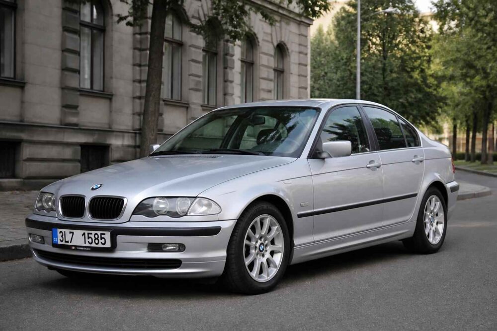 Srebrne BMW serii 3 zaparkowane przy zabytkowym budynku i alei drzew