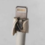 Zniszczona końcówka Lightning białego kabla z odsłoniętymi przewodami